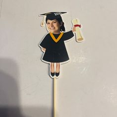 a girl in graduation cap and gown holding a diploma sticker on a white surface