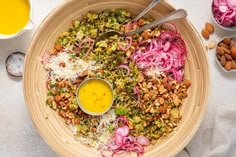 a wooden bowl filled with lots of food and two spoons on top of it