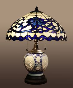 a blue and white table lamp with a glass shade