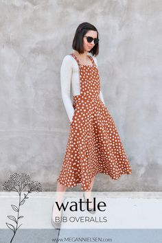 a woman standing in front of a wall wearing a brown and white polka dot dress