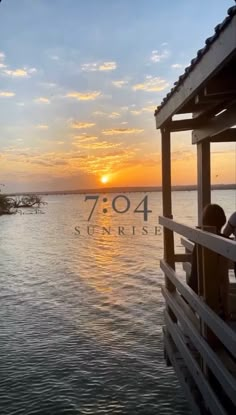 the sun is setting over the water and people are sitting on a dock looking out at the ocean