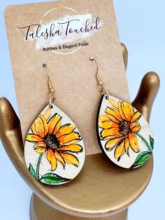 a pair of sunflowers painted on wooden earrings