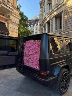 a black jeep with pink flowers in the back door is parked next to another vehicle