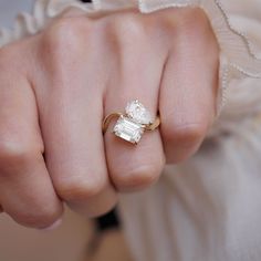 a close up of a person's hand wearing a ring with a diamond on it