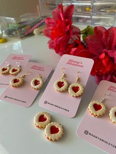 three small heart shaped cookies are sitting on a table next to red flowers and cards