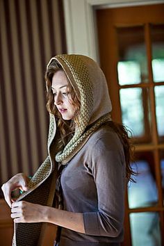 a woman wearing a hood and scarf holding a cell phone