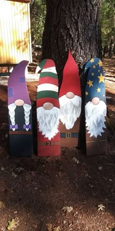 three wooden gnomes sitting next to a tree