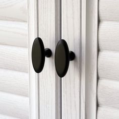 two black knobs on a white door