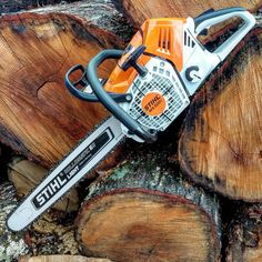 an orange and black chainsaw sitting on top of wood