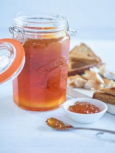 a glass jar filled with liquid next to bread and jam