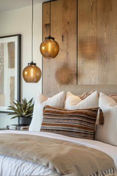 a bedroom with wooden headboard and two hanging lights above the bed in front of it