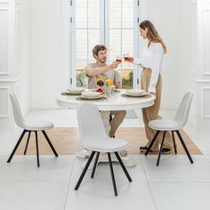 a man and woman sitting at a table with food in front of them, drinking wine