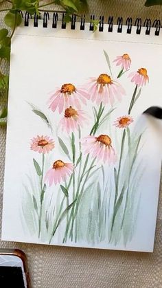 a drawing of pink flowers on a piece of paper next to a cell phone and plant