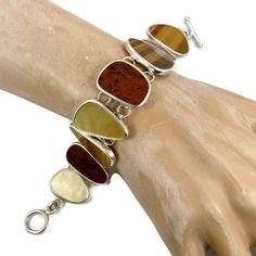 "What a stunning selection of stones this bracelet has! This is a vintage sterling silver bracelet that is created with glowing brown tiger eye, mother-of-pearl and deep red and black jasper stones! This is a designer piece by Whitney Kelly. The earthy shades make up a beautiful color selection. They are set into a sterling bezels. The pieces are nice and big. The silver is shiny. The bracelet conforms easily to your wrist so it is comfortable to wear. The clasp is a toggle. Beautiful piece to w Collectible Brown Jewelry With Natural Stones, Brown Natural Stones Jewelry For Collectors, Brown Gemstone Bracelet, Black Jasper, Brown Tiger, Brown Tiger Eye, Pearl Vintage, Vintage Bracelet, Bracelet Sterling Silver