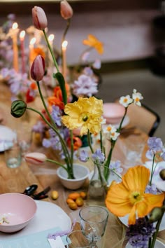 a wooden table topped with lots of plates and flowers on top of each other next to candles