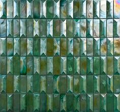 a green glass mosaic tile wall that looks like it is made out of many different shapes and sizes