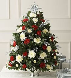 a christmas tree with red, white and green flowers in it sitting on a table