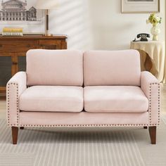 a pink couch sitting on top of a carpeted floor next to a wooden table