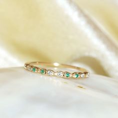 a close up view of a wedding band with emeralds and white diamonds on it