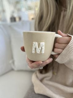 a woman holding a coffee cup with the letter m on it