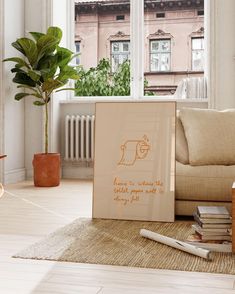 a living room area with a couch, coffee table and books on the floor in front of a window