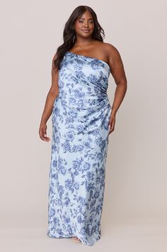 a woman wearing a blue and white floral print dress with one shoulder draped over her shoulders