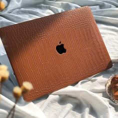 an apple laptop sitting on top of a bed next to a pair of slippers