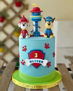 a birthday cake with two dogs on top and a tower in the middle, sitting on a wooden table