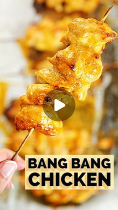 a person is holding a skewer with food on it and the words bang bang chicken