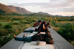 people are sitting on the back of a truck in the middle of an open field