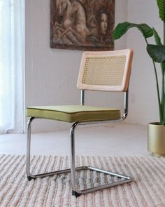 a chair sitting on top of a rug next to a potted plant