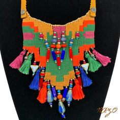 a multicolored necklace with tassels and beads on a black mannequin