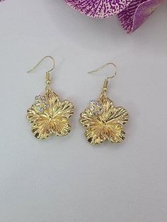 Pretty hibiscus flower earrings with crystal accents. Tarnish resistant ear hooks. 14kt Gold 'pinoy' /filipino Sunkiss Earrings, Gold Beach Jewelry With Flower Charm, Gold Jewelry With Flower Charm For Beach, Elegant Flower-shaped Earrings For Beach, Elegant Flower Shaped Earrings For Beach, Elegant Dangle Flower Earrings For Beach, Gold Flower Jewelry For Beach, Elegant Flower-shaped Beach Earrings, Gold Flower-shaped Earrings For Beach