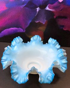 a blue and white bowl sitting on top of a table next to a purple flower