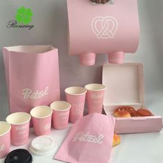 pink paper bags with donuts in them and coffee cups on the table next to each other