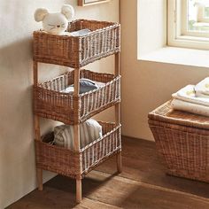 a wicker shelf with baskets on it next to a window and stuffed animal in the corner