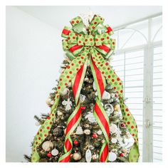 a decorated christmas tree with red, green and white ribbons on it's top