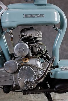 an old blue motorcycle engine sitting on the ground