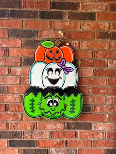 a brick wall with a sign on it that says happy halloween and two pumpkins