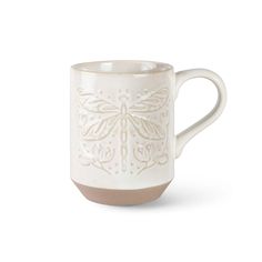 a white mug with a dragonfly design on it