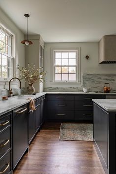 a large kitchen with black cabinets and white counter tops, wood flooring and an area rug