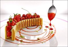 a piece of cake sitting on top of a white plate with strawberries next to it