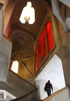 a man is walking up some stairs in a building with red light coming from the windows