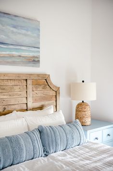 a bedroom with a bed, nightstand and painting on the wall above it's headboard