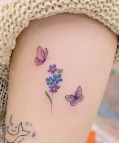 a woman's thigh with purple flowers and butterflies on her left side ribcage