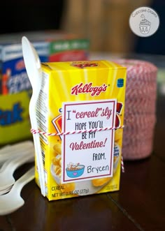 a carton of cereal sitting on top of a table next to a fork and spoon