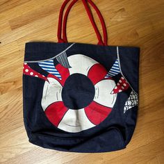 a blue bag with a life preserver on it sitting on a wooden floor next to a pair of scissors