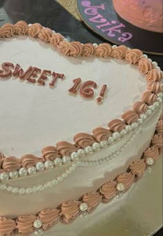 a heart shaped cake with the words sweet 16 on it and pearls around the edges