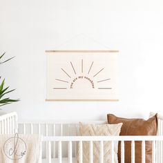 a white crib with a brown pillow and some plants