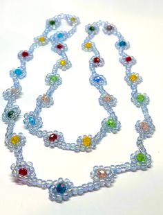 a multicolored glass beaded necklace on a white surface with spacers in the middle